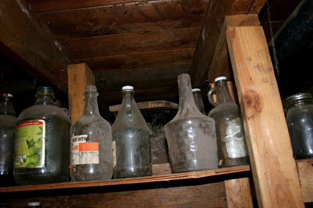 old dusty glass containers on wooden shelf