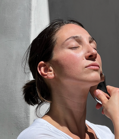 Woman using Blumenes Stainless Steel Gua Sha to sculpt her jawline.