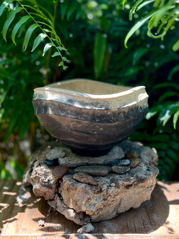 A bowl by Osa Atoe. Made with wild clay and blackened with smoke, the bowl features an undulating rim.