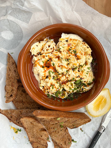 Burrata with Chilli Oil Herbs and Lemon Zest and Juice. Pictured in a small terracotta dish, with wholemeal bruschetta.  Photo and recipe by Laura Faire