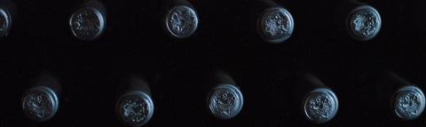 moody image of wine bottle tops stacked in cellar, all dark