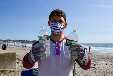 Man holding two plastic water bottles at ocean clean-up