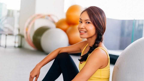 swiss-ball-femme-asiatique-assise-sourirante-salle-de-fitness