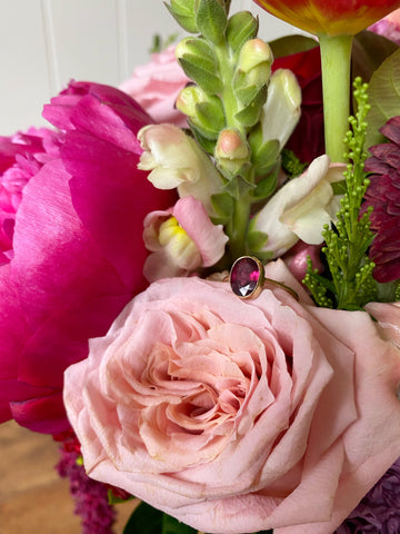 Garnet and gold ring atop a bunch of flowers 