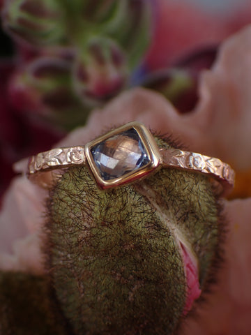 Sapphire Engagement Ring sitting on flower bulb with flowers in background 