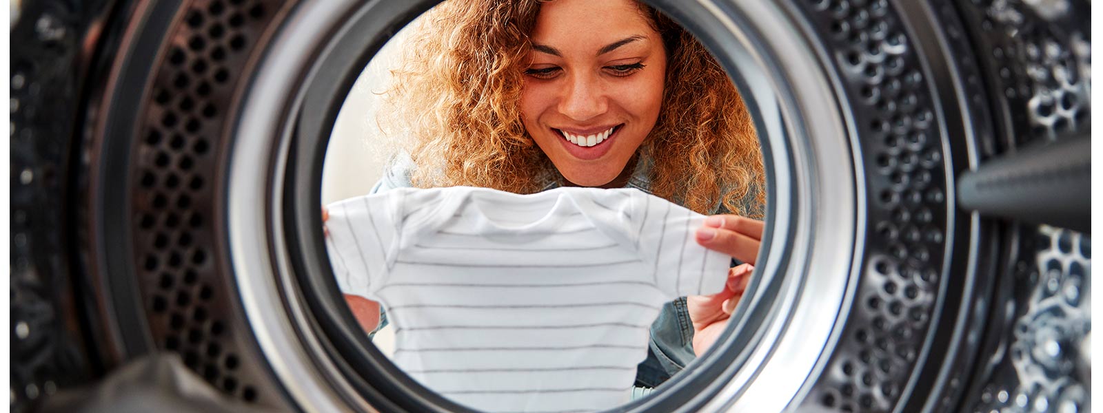 femme regardant à l’intérieur d'une machine pendant la lessive de bébé