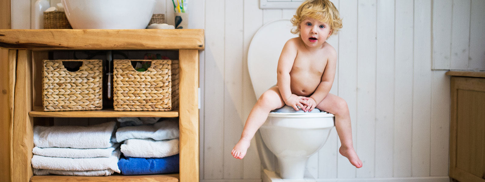 un enfant sur les toilettes avec des paniers à linge dans des étagères