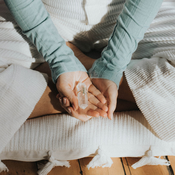 women meditating holding crystal