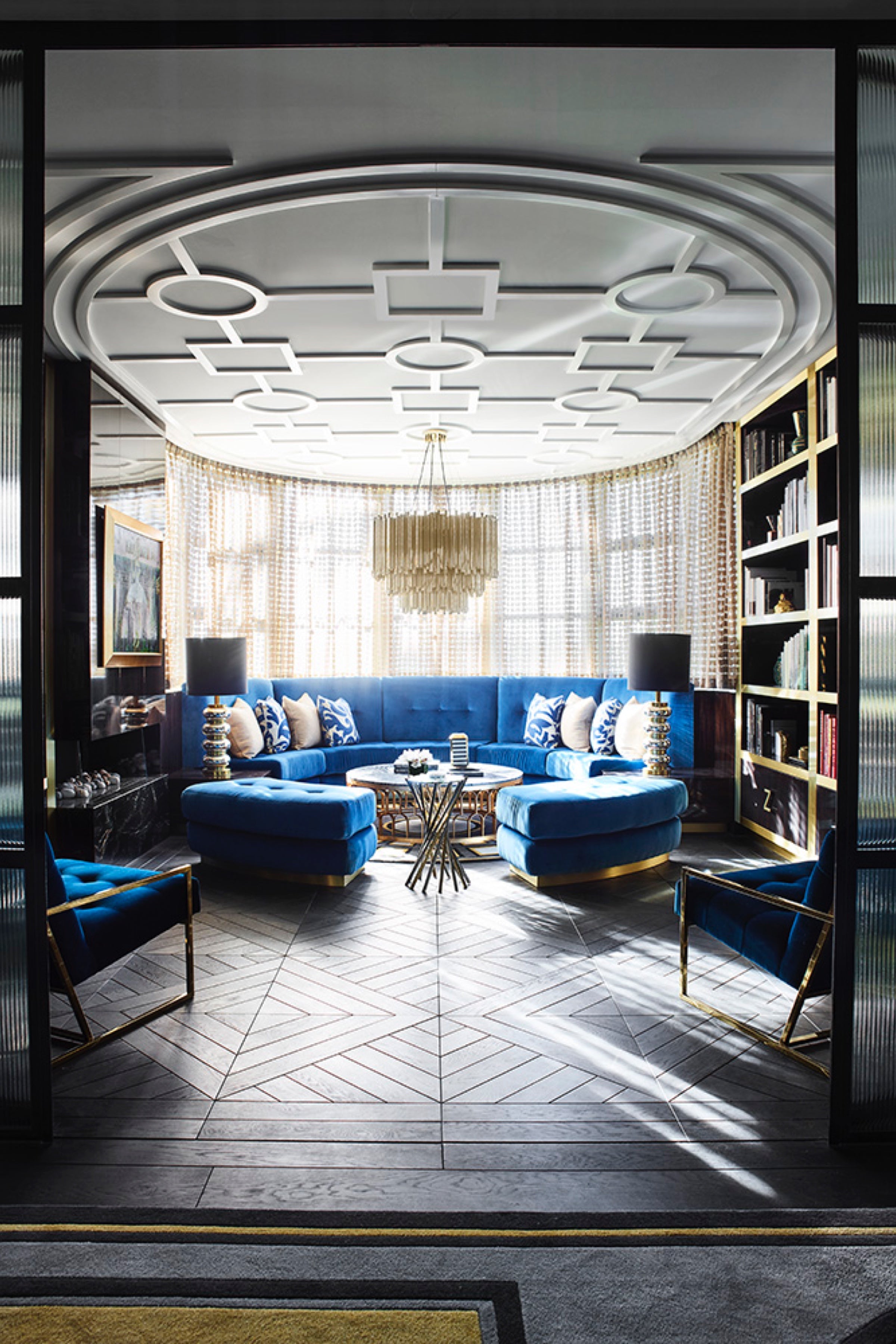 Living room with blue curved sofa and geometric ceiling design