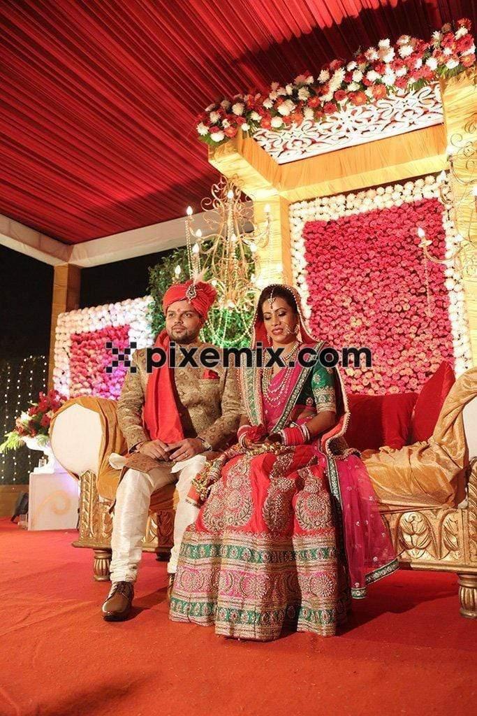 Indian bride and groom sitting on stage image