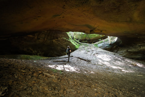 Hiker looking up through the skylight inside of yahoo arch in big south fork of kentucky