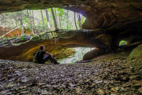 Hiker sitting underneath Yahoo arch in big south fork of kentucky