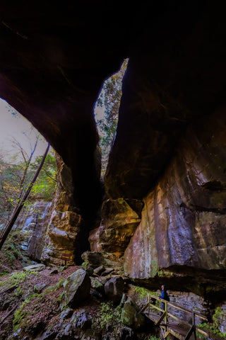 Hiker standing below fern bridge arch in Carter caves state park Kentucky 