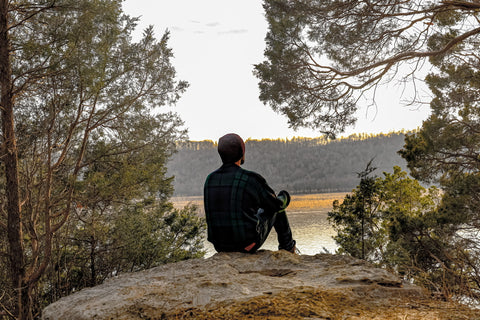 man perched on cliff overlook watching sunset in o'bannon woods state park