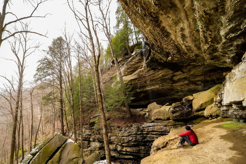 hiker sitting on cliff below anglin falls in kentucky