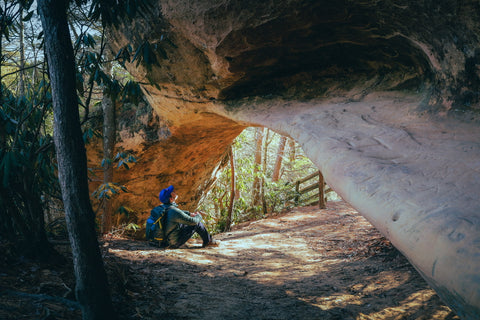 hiker sitting under Indian arch along the Sheltowee trace trail in the red river gorge of Kentucky 