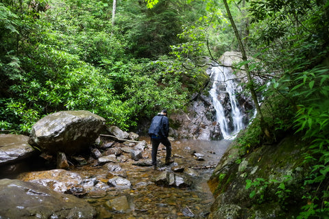 hiker viewing waterfall cascading down boulders along cabin creek trail in grayson highlands state park