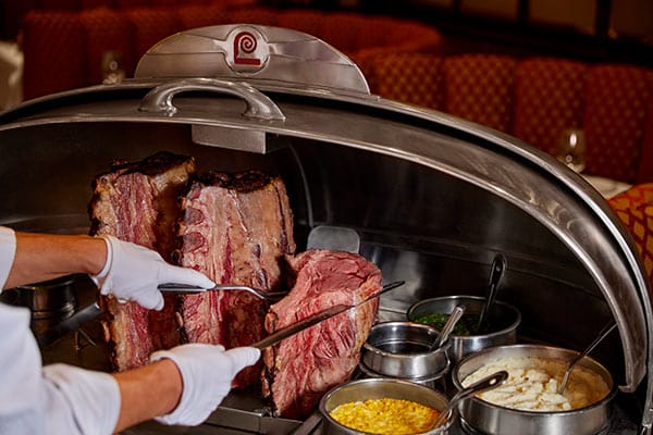 Lawry's carver carving off a cut of prime rib from his silver cart