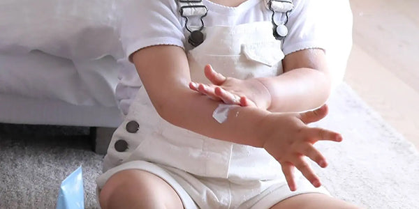 Toddler applying sunscreen to arm