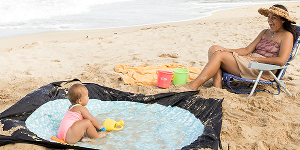 Baby playing in puddle-style kiddie pool with mom watching.