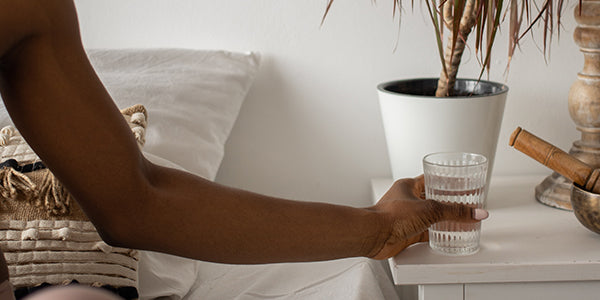 Woman grabbing a glass of water while in bed