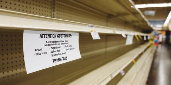 Empty store shelves with a warning notice