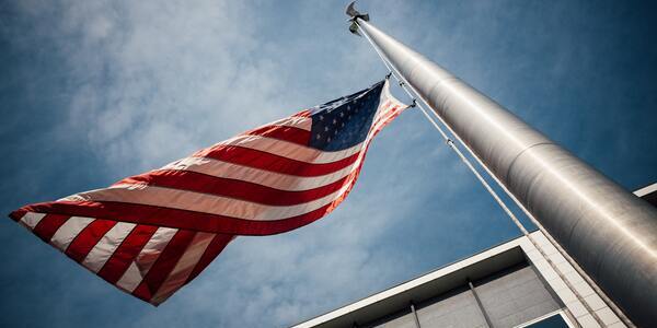 Upwards view of the USA flag on a pole with the wind blowing against it