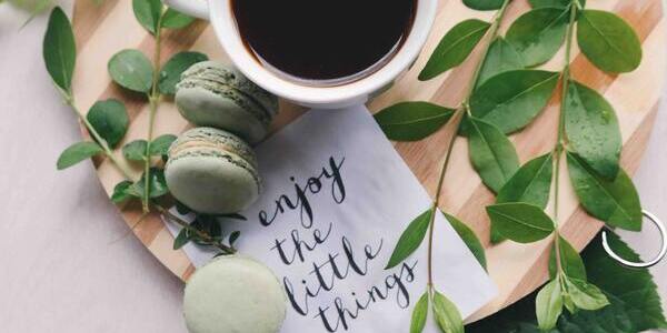 A cup of coffee with a note that says 'enjoy the little things'