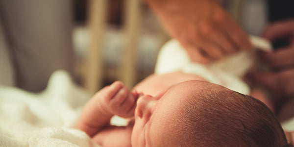 Mother changing newborn girl's diaper