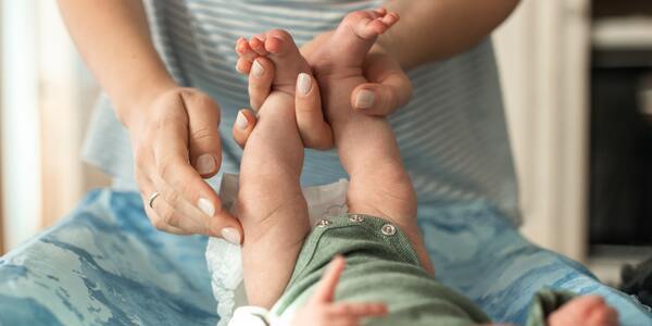 Woman holding a baby's feet in one hand for a diaper change