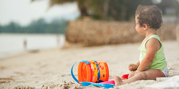 Baby on the beach with a sand bucket