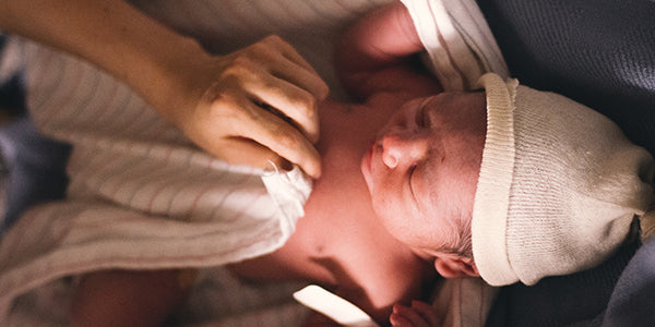 Mother covering naked newborn with blanket