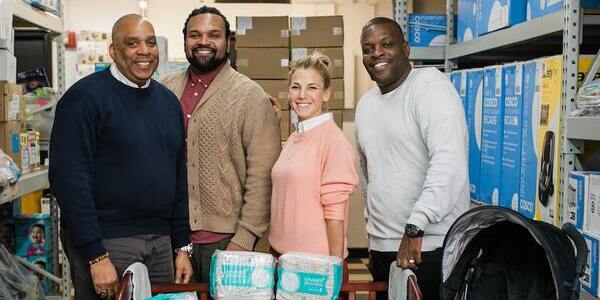 Good+Foundation team members standing in a storage room next to diapers