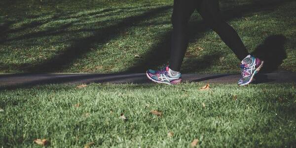 Woman in running shoes walking alongside grass