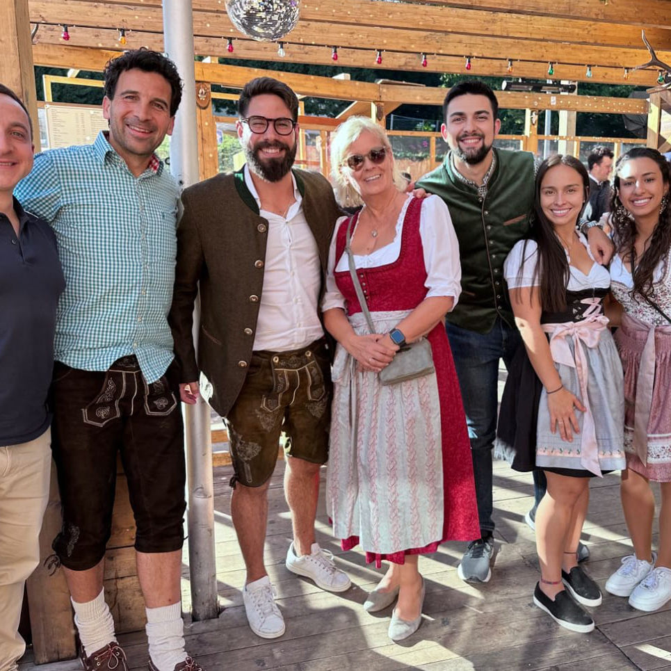 Ein fröhliches SanaExpert Team in traditioneller bayerischer Tracht genießt das Oktoberfest, mit strahlenden Gesichtern und einem freundlichen Ambiente.