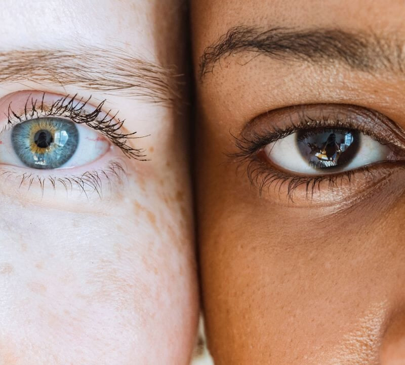 Nahaufnahme zweier Augen, links ein Auge mit blauer Iris und rechts ein Auge mit brauner Iris, nebeneinander, symbolisiert Vielfalt und Einzigartigkeit der menschlichen Augenfarben.
