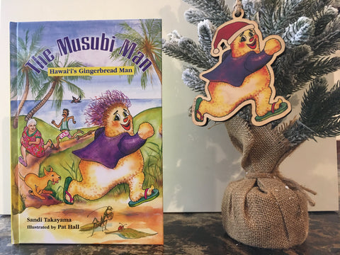 The Musubi Man book with a matching wood ornament hanging from a table top Christmas tree