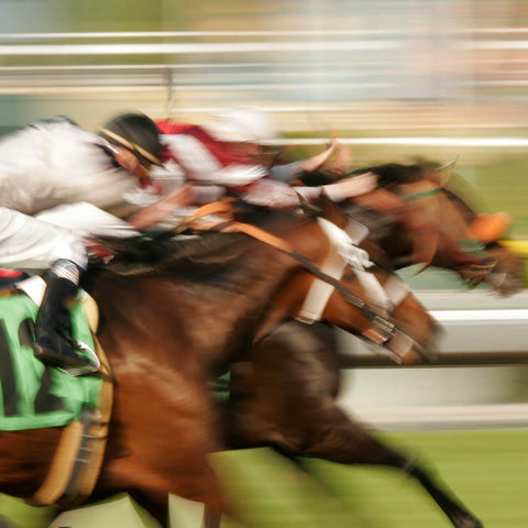 Blurred image of running racehorses with riders