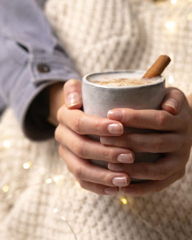 Winter oat Latte in beiden Händen haltend