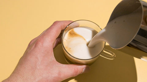 Cremiger Milchschaum, der in Kaffeetasse gefülllt wird