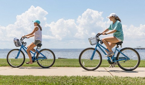 two women riding bikes along the beach