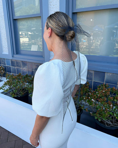 Alexandra Nea at TAB Everest Day wearing a white dress and navy veiling bow