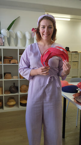 Lauren Ritchie holding the red Stanley Bramble Headpiece in her Collins Street Studio
