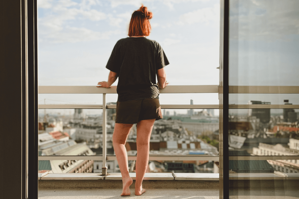 Kim standing on a balcony looking out over Vienna, seen through an open glass door.