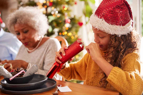 Girl wearing a santa hat looking into an open Christmas cracker
