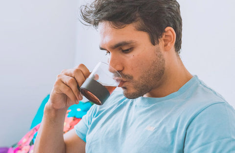 a man whose sitting drinks tea from a transparent cup