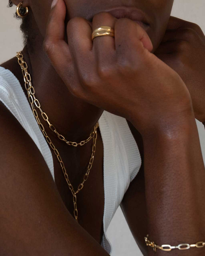 Dunkelhäutiges Model trägt zwei Ketten, einen Ring und ein Armband in Gold Vermeil