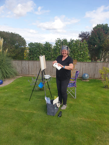 Artist stood at an easel in a garden