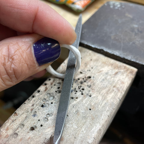 Amy Delson filing a rough casting of a toggle clasp