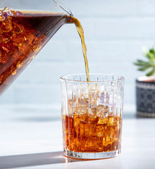 Pouring coffee from a pitcher over ice.